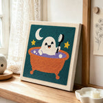 Cute ghost taking bubble bath punch needle artwork displayed on a table