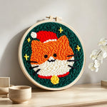 Cute orange cat in santa hat punch needle artwork displayed on a table