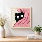 Finished cute peeking kitten in pink blanket artwork displayed on a wall