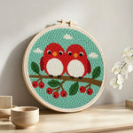 Cute red birds on berry branch punch needle artwork displayed on a table