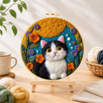 Finished cute tuxedo cat and bright flowers needle felting displayed on a wooden easel