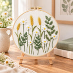 Daisy and wheat embroidery kit finished hoop displayed on a wooden stand as cozy tabletop decor