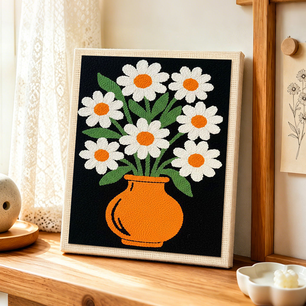 Daisy flowers in orange vase punch needle artwork displayed on a table