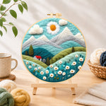 Finished daisy sun and red cottage in the alps needle felting displayed on a wooden easel