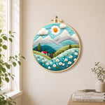 Daisy sun and red cottage in the alps needle felt wall art displayed in a bright home interior