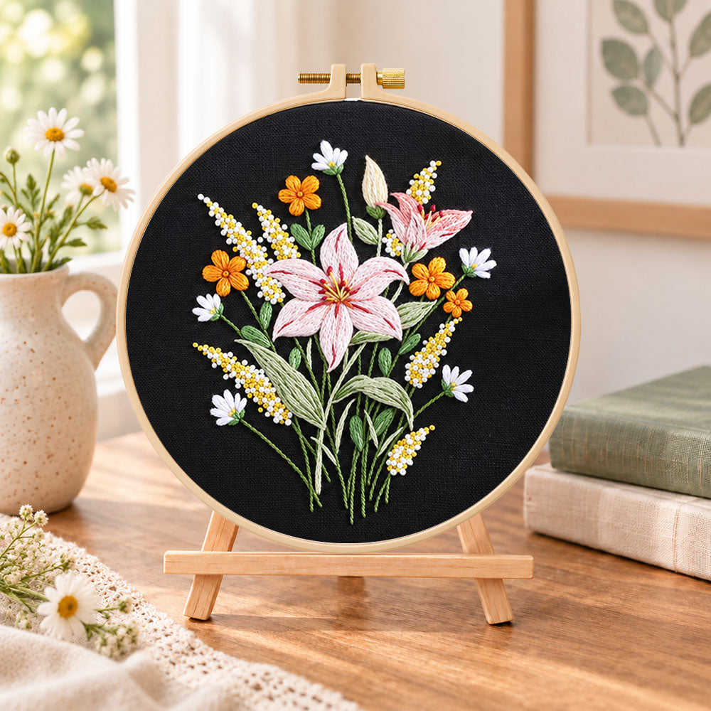 Dark background lilies embroidery kit finished hoop displayed on a wooden stand as cozy tabletop decor