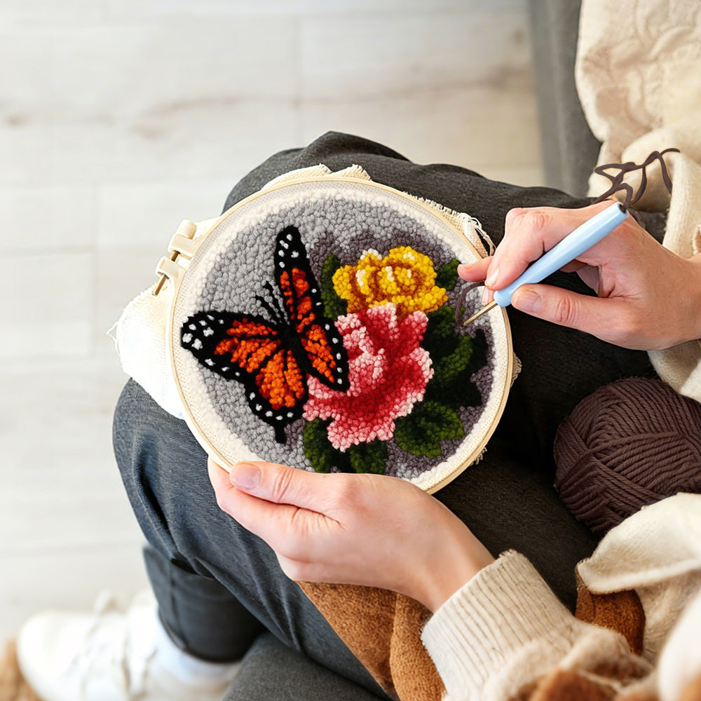 Creating handmade dark-colored butterfly and flowers punch needle artwork