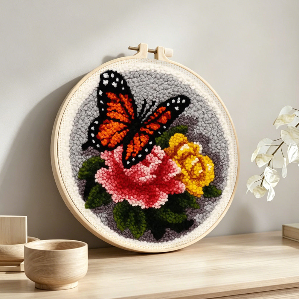 Dark-colored butterfly and flowers punch needle artwork displayed on a table