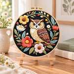 Dark floral owl embroidery kit finished hoop displayed on a wooden stand as cozy tabletop decor