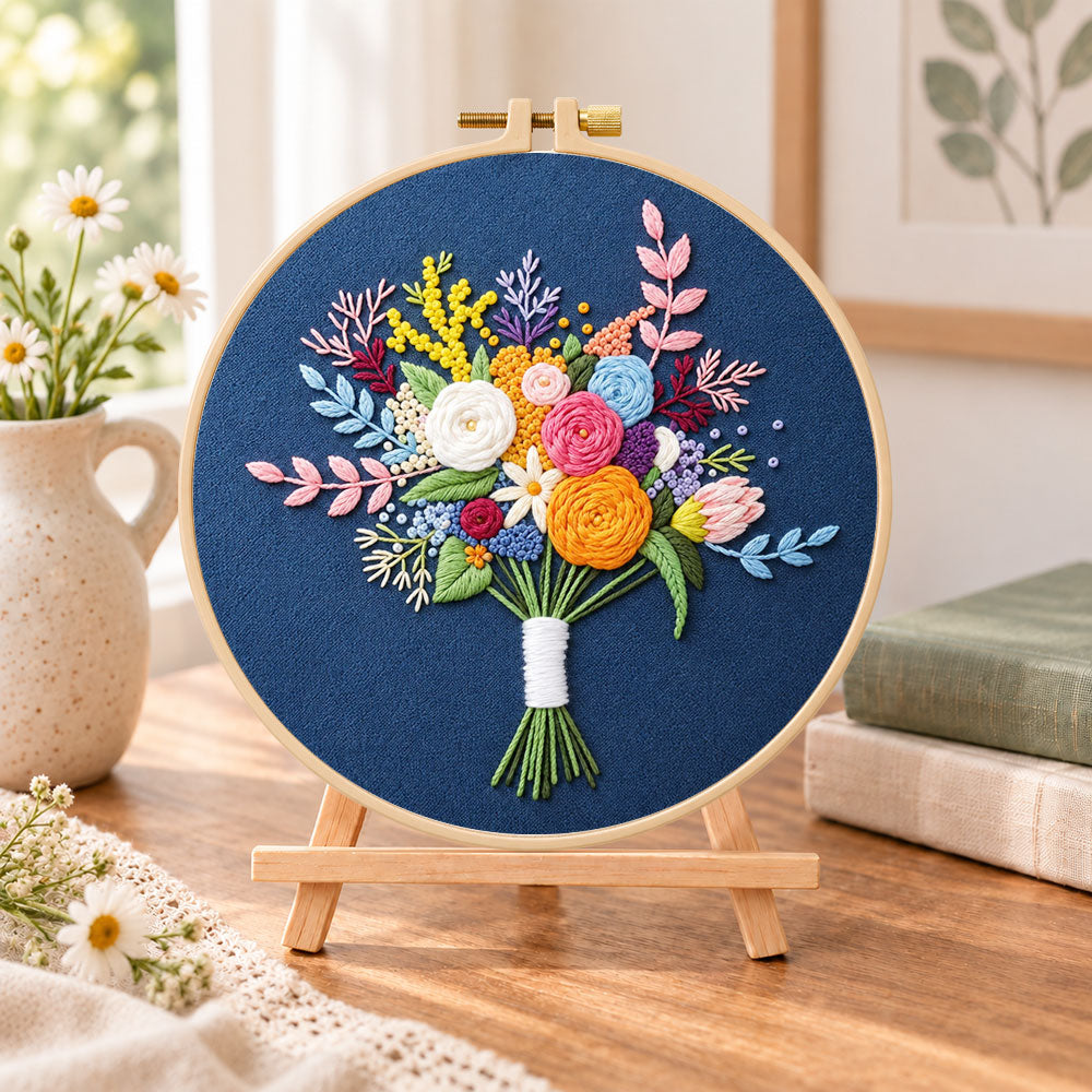 Deep blue mixed flower bouquet embroidery kit finished hoop displayed on a wooden stand as cozy tabletop decor