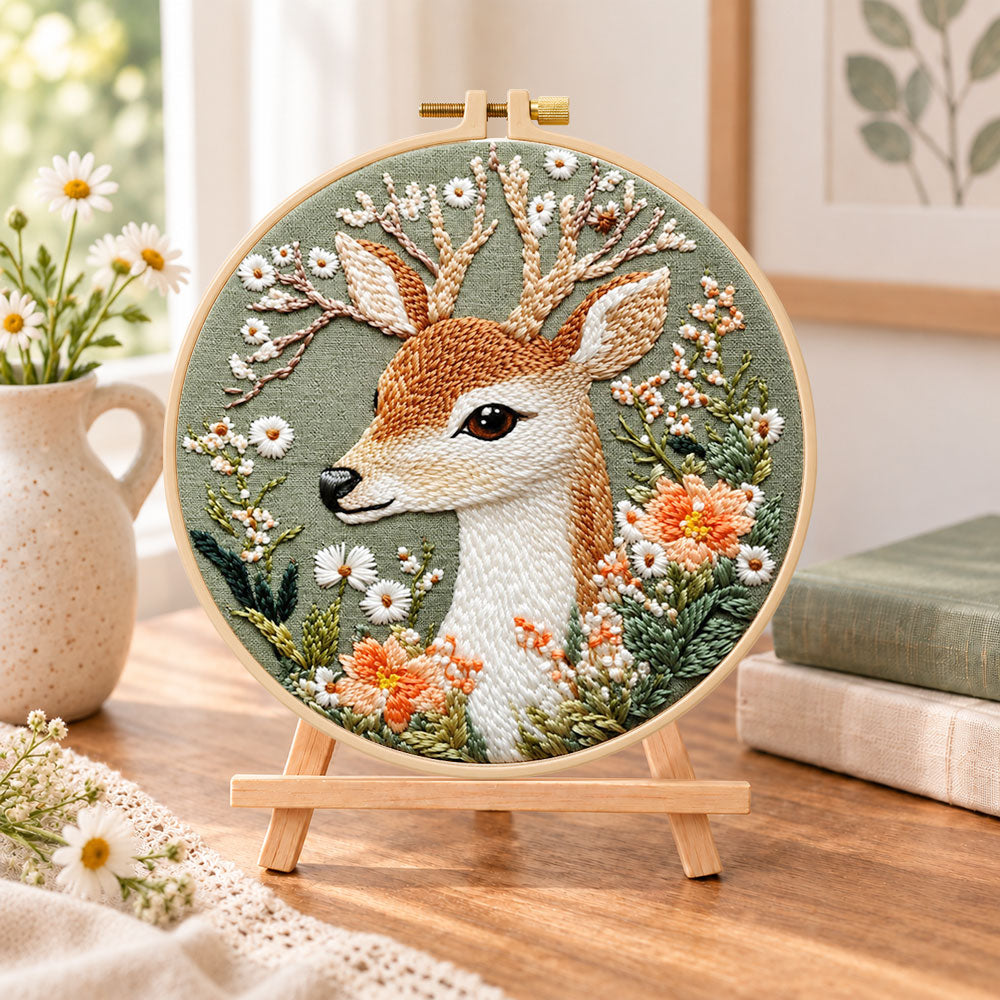 Deer and wild daisies embroidery kit finished hoop displayed on a wooden stand as cozy tabletop decor