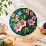 Finished delicate pink flowers on dark green needle felting displayed on a wooden easel