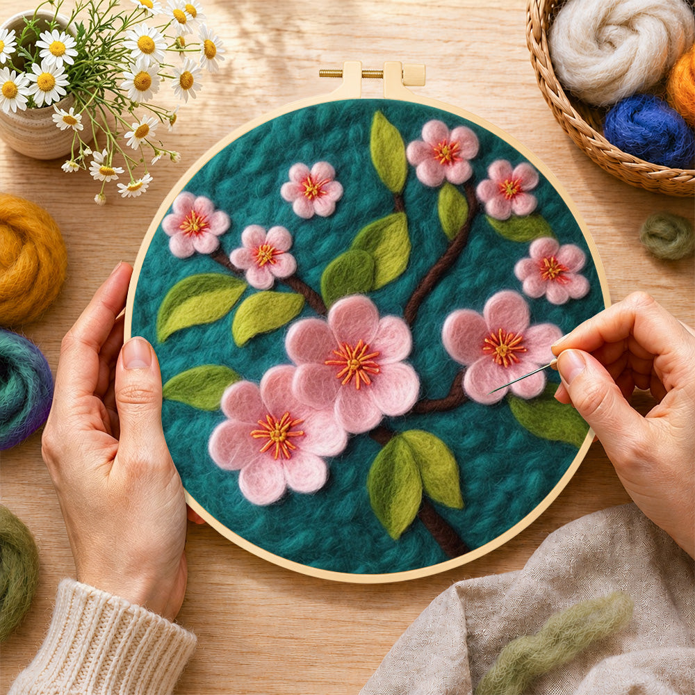 Creating the delicate pink flowers on dark green wool painting by hand with a felting needle