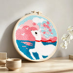 Dreamy clouds, sea, and white deer punch needle artwork displayed on a table