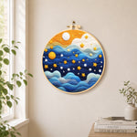 Drifting blue clouds and yellow stars needle felt wall art displayed in a bright home interior