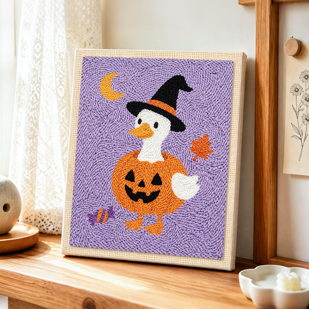 Duck in pumpkin witch outfit punch needle artwork displayed on a table