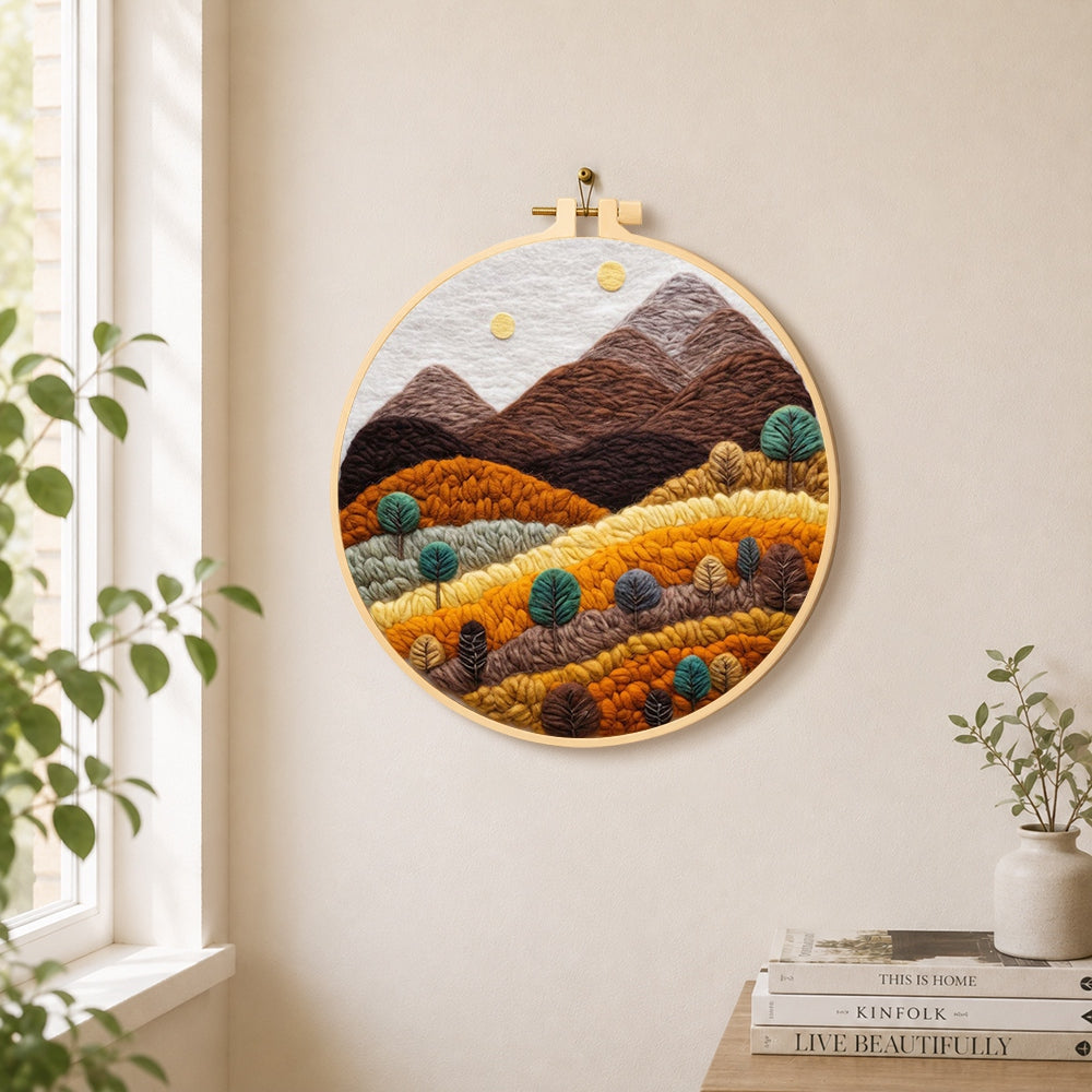Earthy brown and burnt orange mountains with trees needle felt wall art displayed in a bright home interior