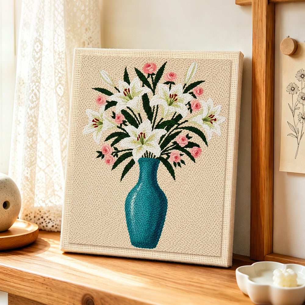Elegant lily and pink roses in blue vase punch needle artwork displayed on a table