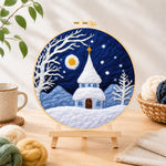 Finished fairy tale snowy spire cottage needle felting displayed on a wooden easel