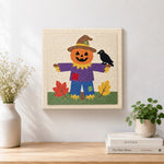 Finished fall pumpkin scarecrow artwork displayed on a wall
