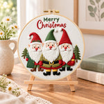 Festive christmas gnomes embroidery kit finished hoop displayed on a wooden stand as cozy tabletop decor
