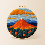 Fiery red volcano and deep blue trees needle felting kit for beginners with a round wooden frame
