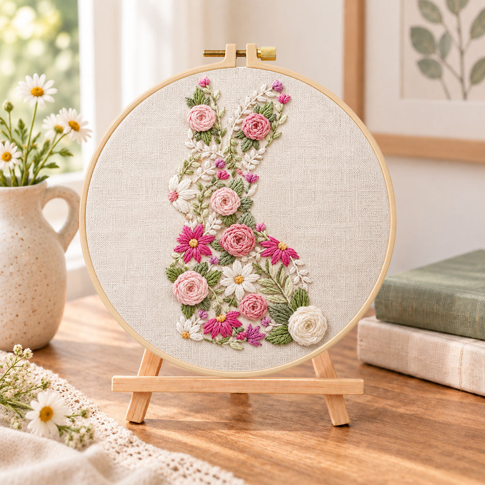 Floral bunny silhouette embroidery kit finished hoop displayed on a wooden stand as cozy tabletop decor