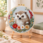 Floral framed hedgehog embroidery kit finished hoop displayed on a wooden stand as cozy tabletop decor
