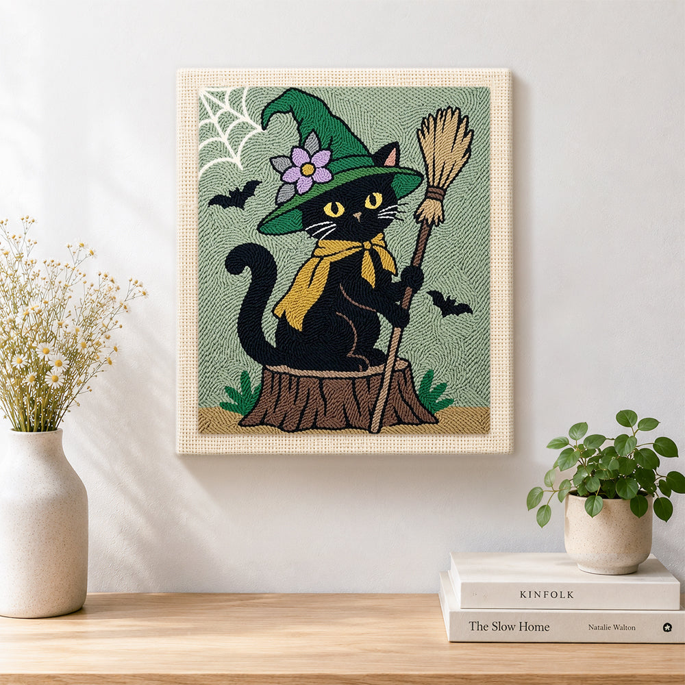 Finished floral‑hat witch cat with broom artwork displayed on a wall