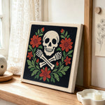 Floral skull and crossbones punch needle artwork displayed on a table