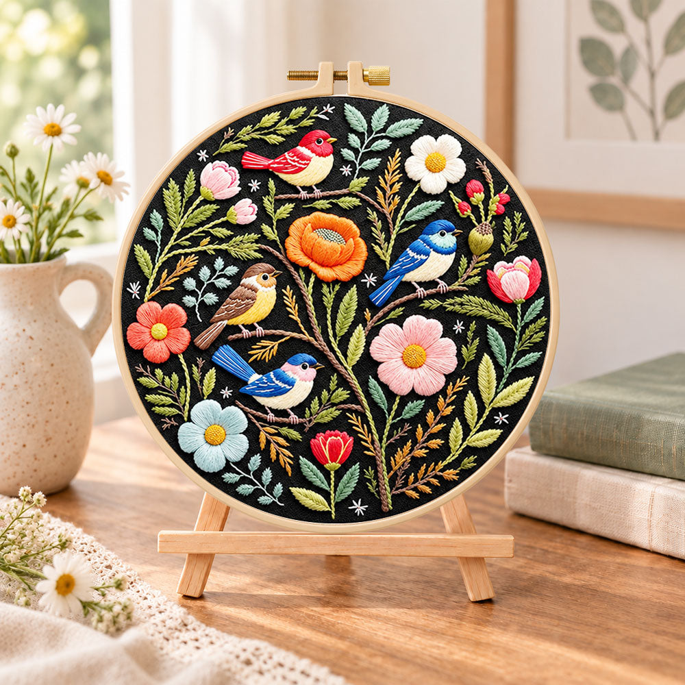 Forest birds and spring blooms embroidery kit finished hoop displayed on a wooden stand as cozy tabletop decor