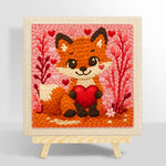 Fox holding a red heart punch needle kit for beginners