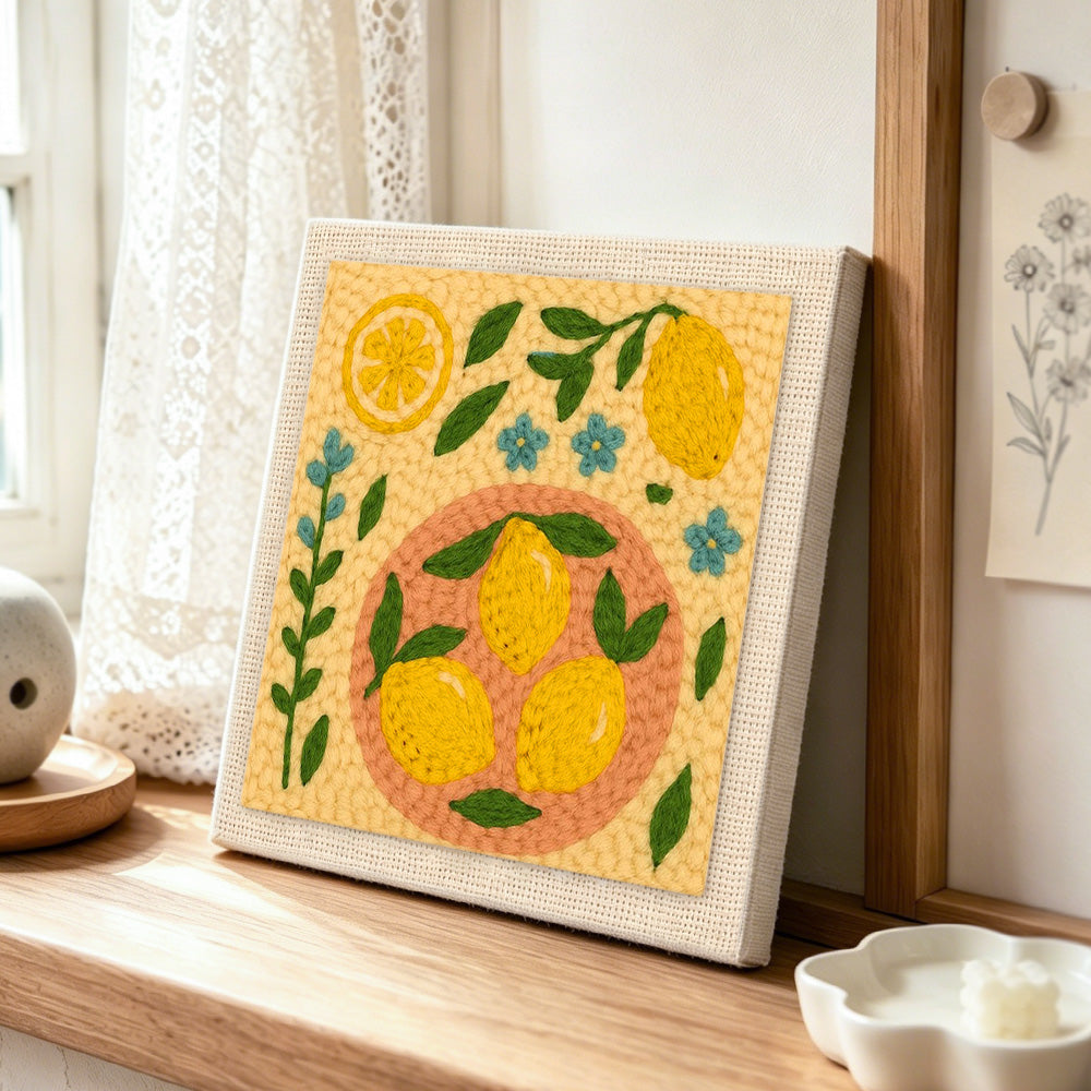 Fresh lemons and little blue flowers punch needle artwork displayed on a table