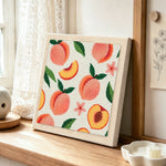 Fresh peaches with leaves punch needle artwork displayed on a table