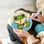 Creating handmade frog holding a flower punch needle artwork