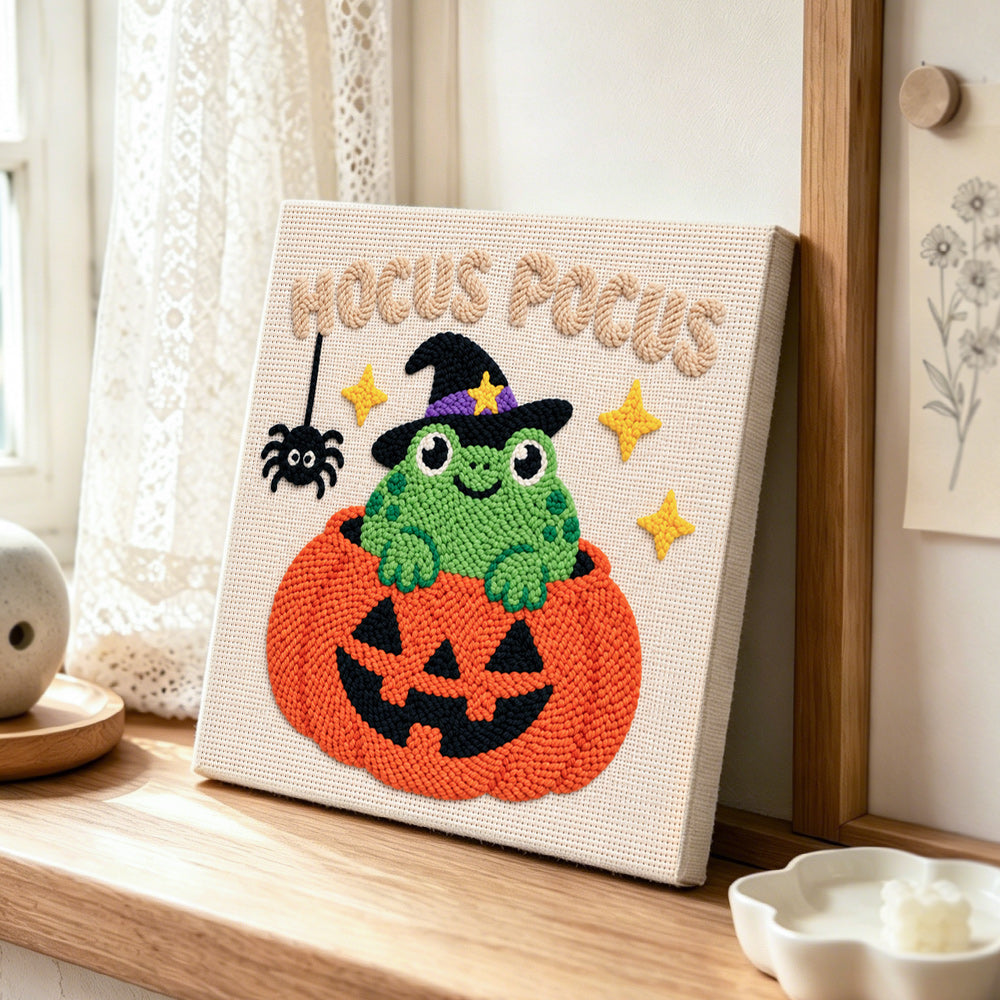 Frog witch inside pumpkin punch needle artwork displayed on a table