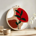 Geometric color block with green vine punch needle artwork displayed on a table