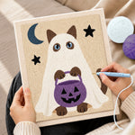 Creating handmade ghost cat holding pumpkin treat bucket punch needle artwork