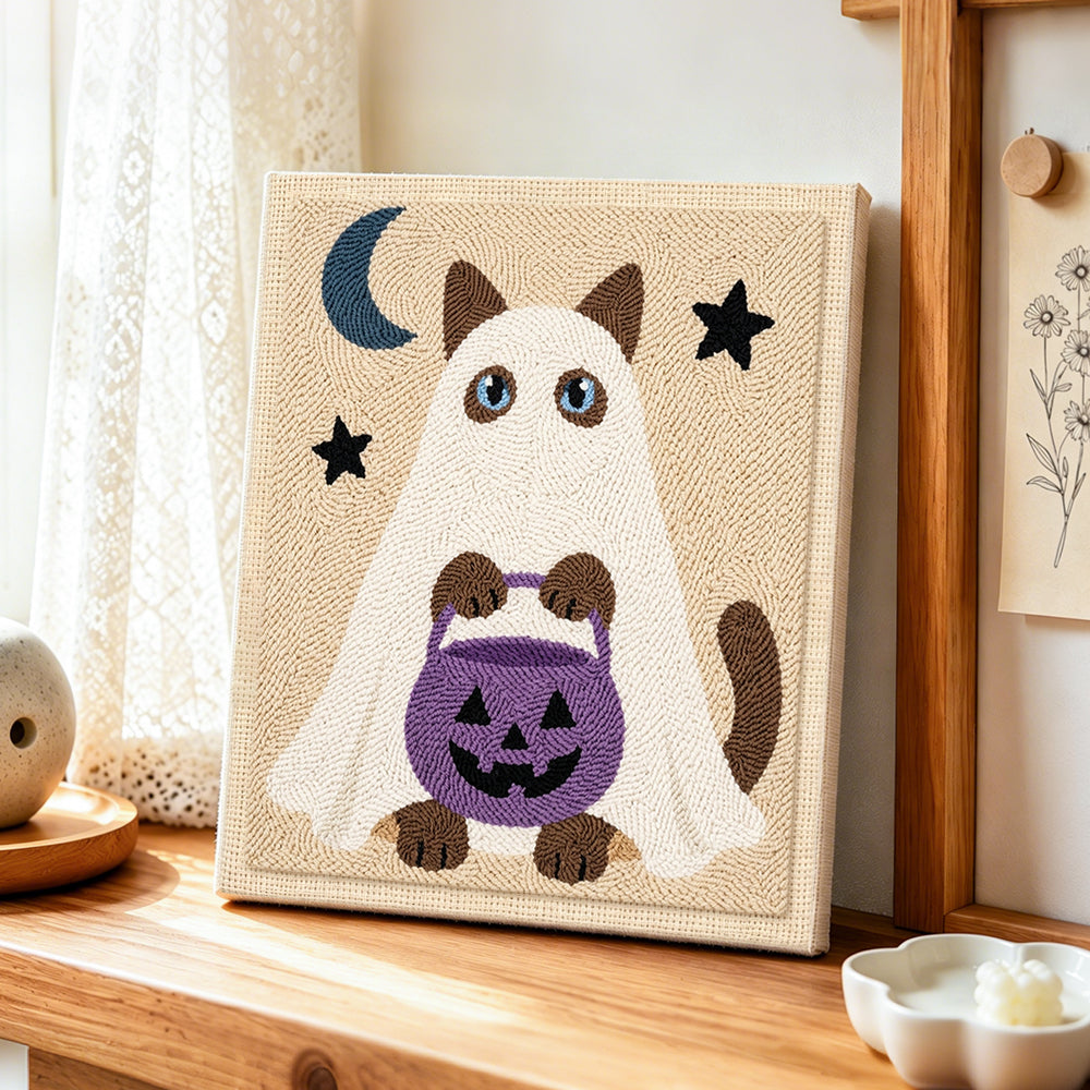 Ghost cat holding pumpkin treat bucket punch needle artwork displayed on a table