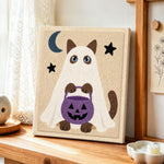 Ghost cat holding pumpkin treat bucket punch needle artwork displayed on a table