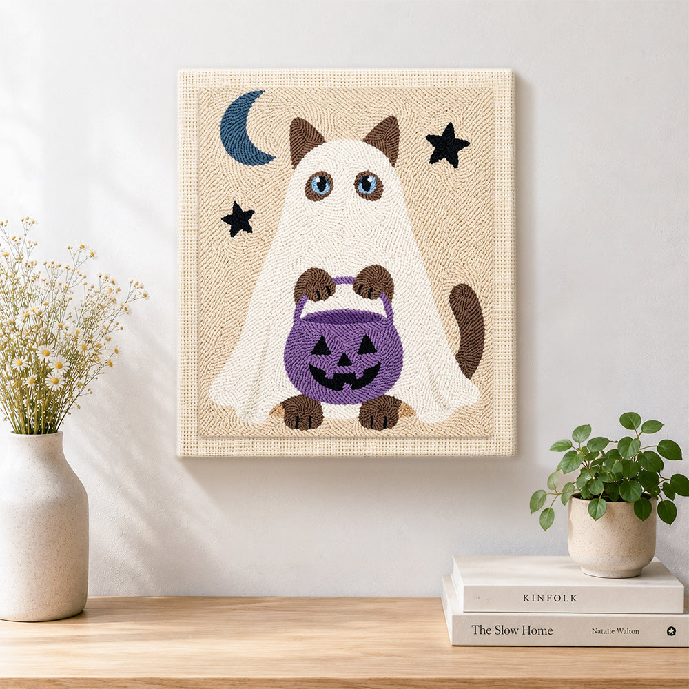 Finished ghost cat holding pumpkin treat bucket artwork displayed on a wall