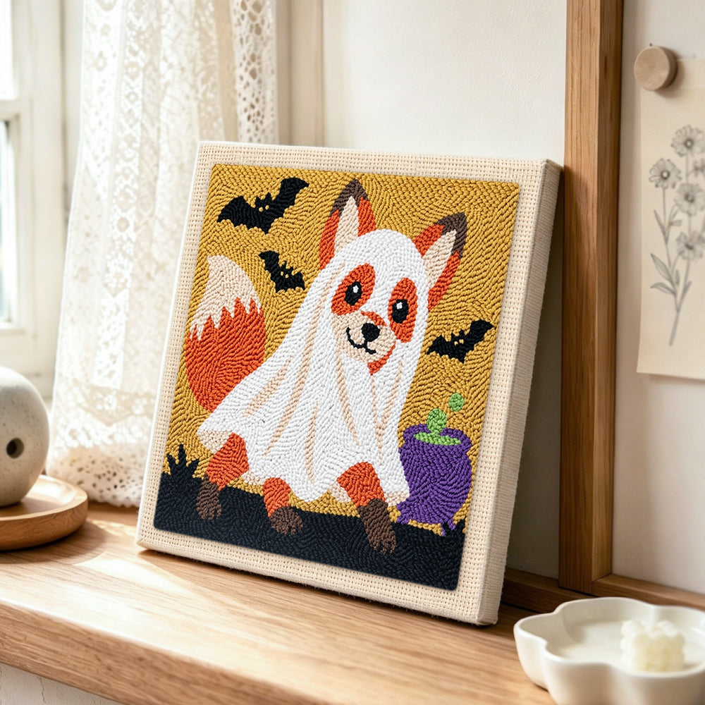 Ghost‑costumed fox punch needle artwork displayed on a table