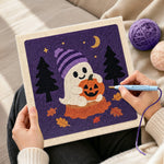 Creating handmade ghost holding pumpkin punch needle artwork