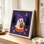 Ghost holding pumpkin punch needle artwork displayed on a table
