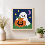 Finished ghost hugging pumpkin artwork displayed on a wall