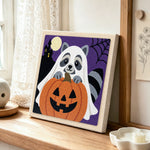 Ghost raccoon and pumpkin punch needle artwork displayed on a table