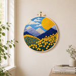 Giant sun, mountains and yellow flowers needle felt wall art displayed in a bright home interior