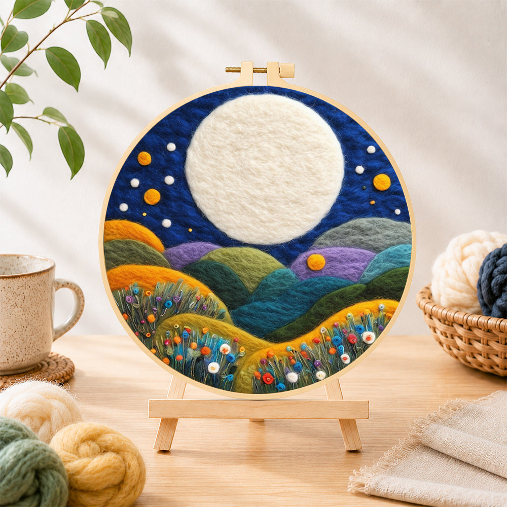 Finished giant white moon over colorful flower hills needle felting displayed on a wooden easel