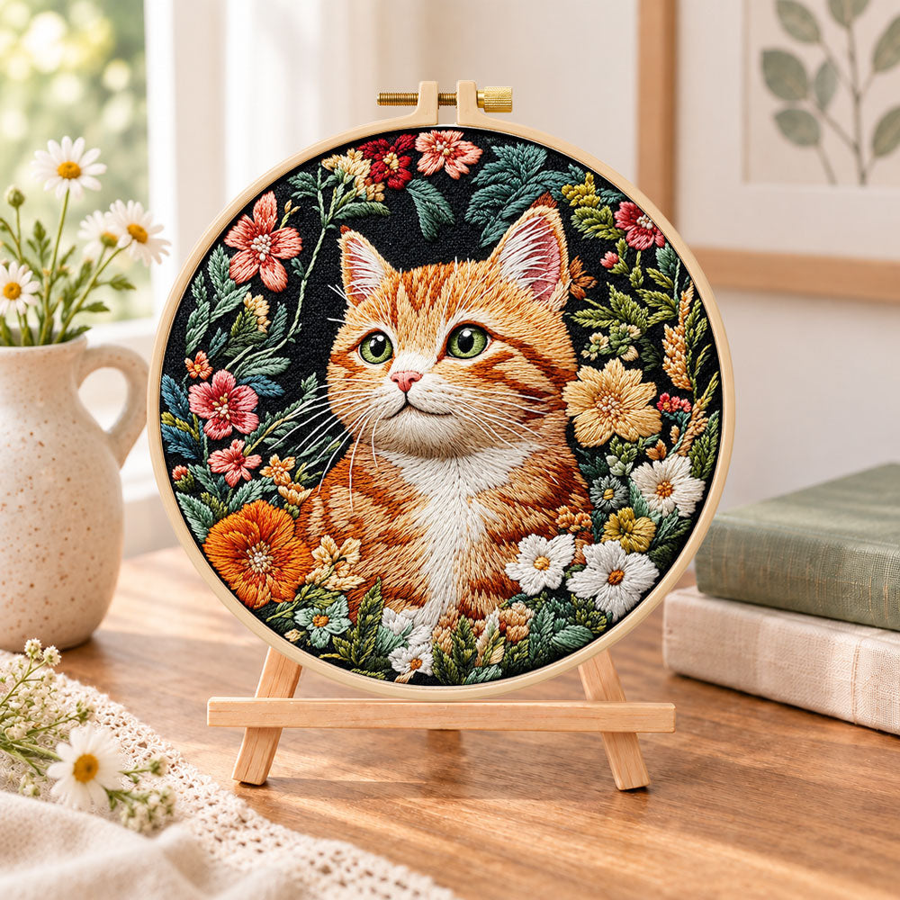 Ginger cat in wild blooms embroidery kit finished hoop displayed on a wooden stand as cozy tabletop decor