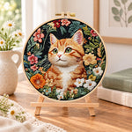 Ginger cat in wild blooms embroidery kit finished hoop displayed on a wooden stand as cozy tabletop decor